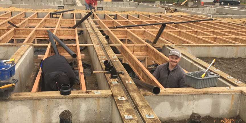 All County crew installing drain piping in a timber-framed home