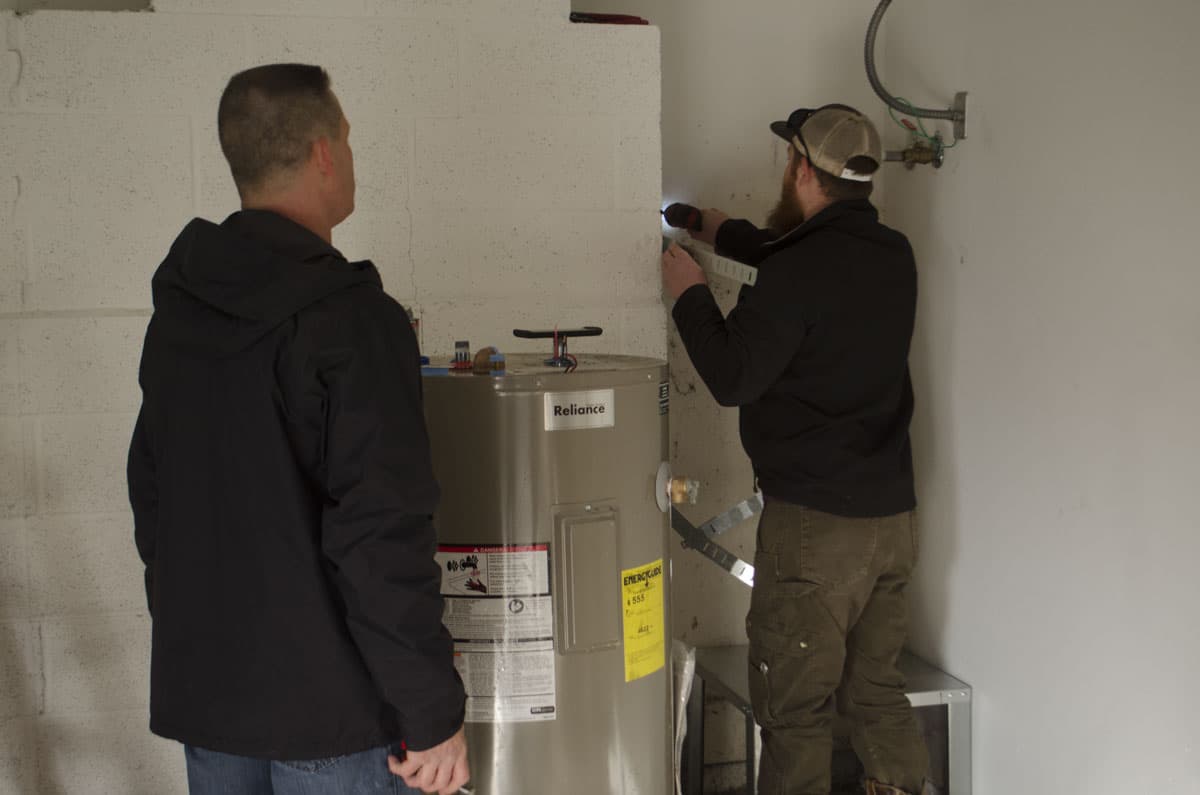 Two All County crew members installing a tank water heater