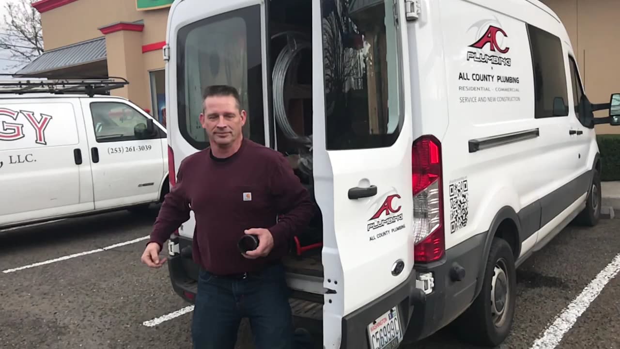 All County plumber preparing for a service call beside a company van