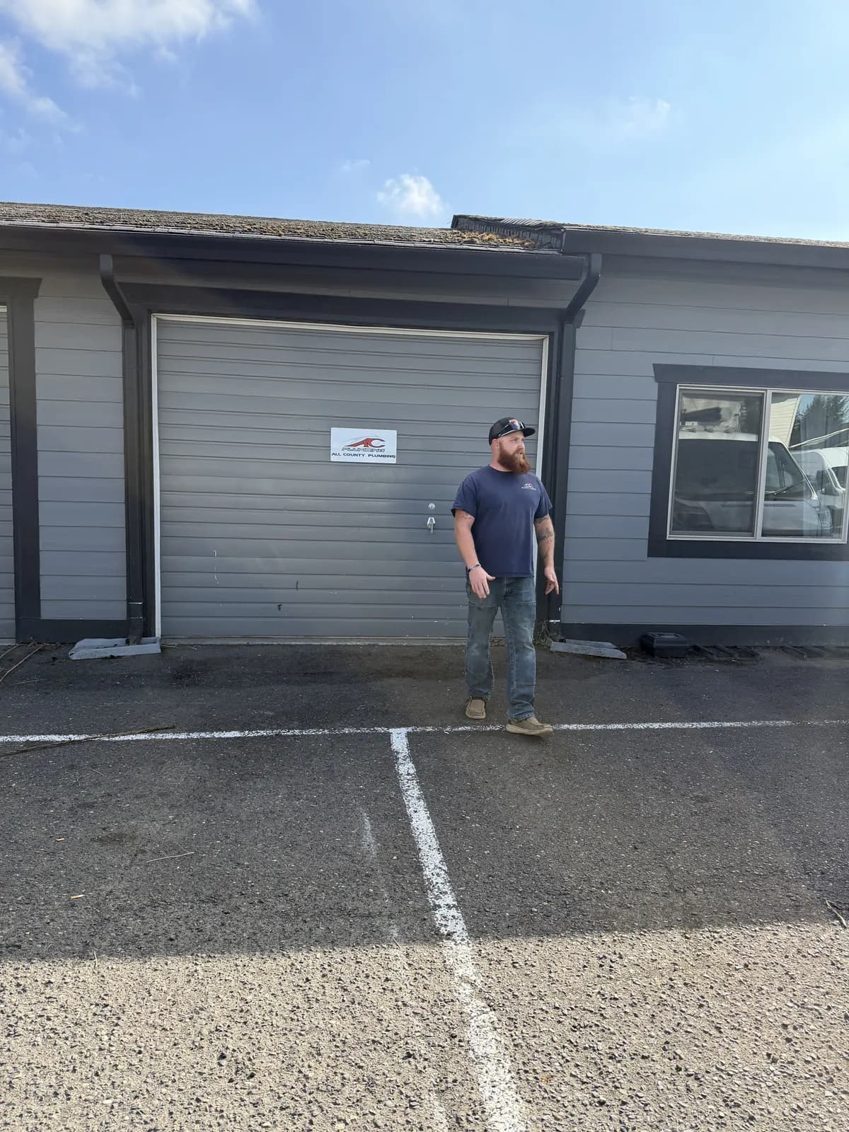 Crew member in a navy All County shirt at the shop roll-up door