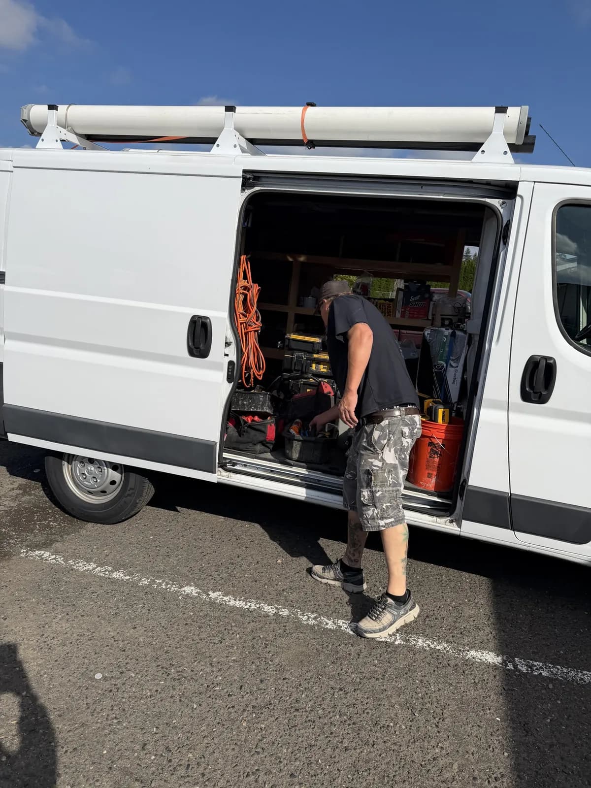 Technician organizing tools and parts through the open side door of a service van